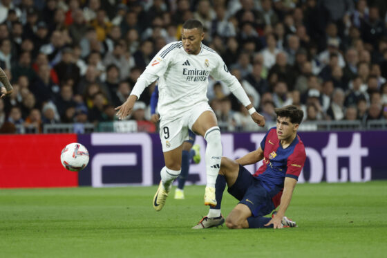 El delantero del Real Madrid Kylian Mbappé (i) lucha con Pau Cubarsí, del FC Barcelona, durante el partido de la jornada 11 de LaLiga EA Sports entre el Real Madrid y el FC Barcelona, este sábado en el estadio Santiago Bernabéu, en Madrid. EFE/Juanjo Martín