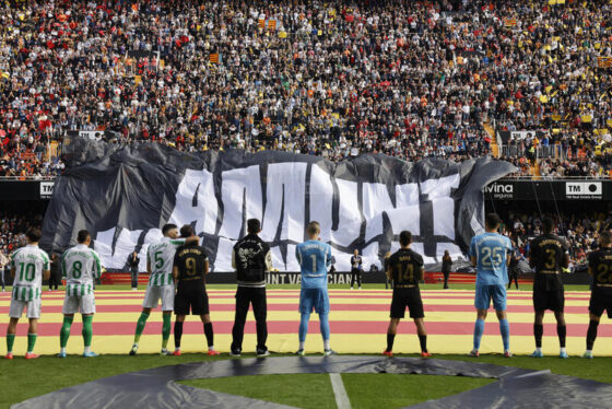 Los jugadores del Valencia y del Real Betis observan el despliegue de una pancarta en homenaje a las víctimas de la dana en Mestalla. EFE/Ana Escobar