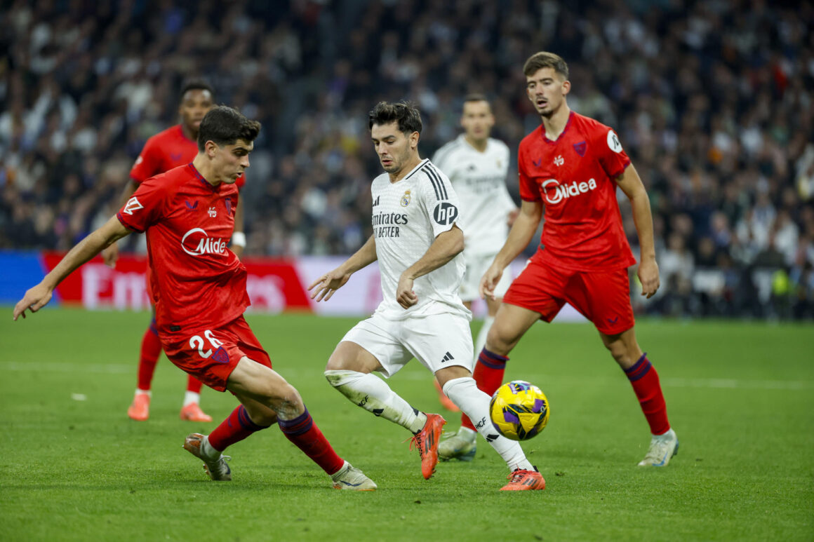 El centrocampista del Real Madrid Brahim Díaz (c) y el delantero del Sevilla Juanlu Sánchez (i)  durante el partido de LaLiga entre el Real Madrid y el Sevilla, este domingo en el estadio Santiago Bernabéu. EFE/ JuanJo Martín