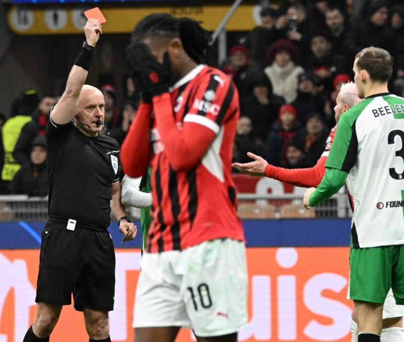 El árbitro polaco Szymon Marciniak muestra la tarjeta roja al defensa del AC Milan Theo Hernandez (d) mientras Rafael Leao se lamenta durante el partido del playoff de acceso a octavos en la UEFA Champions League jugado en el Giuseppe Meazza Stadium en Milan, Italia. EFE/EPA/DANIEL DAL ZENNARO