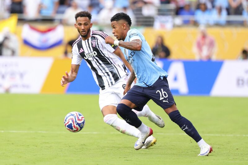 Savinho (d), del Manchester City, avanza con el balón ante la marca de Lloyd Kelly, de Juventus. EFE/EPA/CRISTOBAL HERRERA-ULASHKEVICH