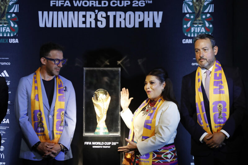 El exfutbolista italiano Alessandro del Piero (i), la jefa de Gobierno de la Ciudad de México, Clara Brugada (c) y el director de FIFA México, Jurgen Mainka (d), posan junto al trofeo de la Copa Mundial de la FIFA, durante la develación del reloj de Mundial este miércoles, en Ciudad de México (México). EFE /Mario Guzmán