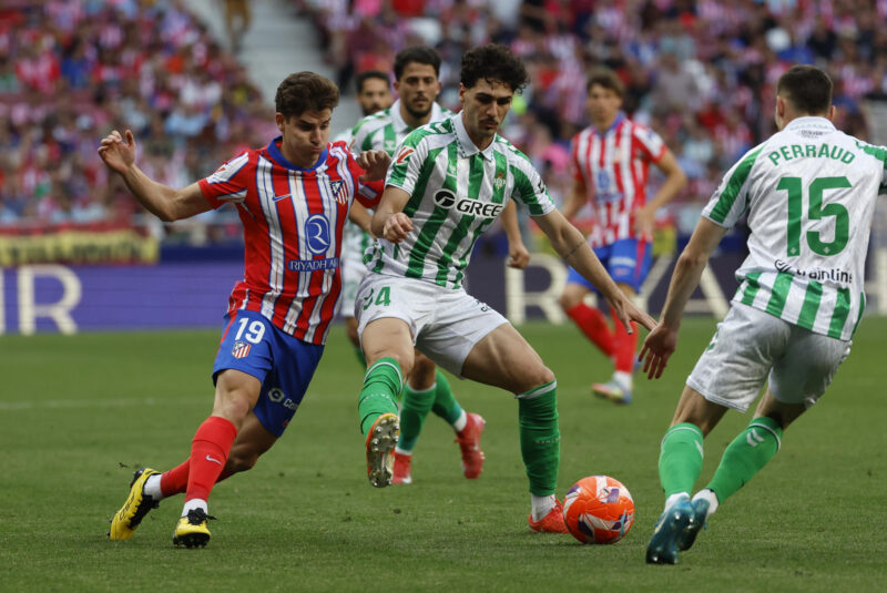 El centrocampista estadounidense Johnny Cardoso (c) disputa la posesión del balón con el delantero argentino del Atlético de Madrid Julián Álvarez (i) durante el partido de la jornada 37 de LaLiga Betis- Atlético de Madrid. EFE/ (Archivo 18/05/2025)/ Mariscal