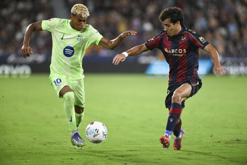 Lamine Yamal estrenará botas con su logotipo frente al Valencia El delantero del Barcelona Lamine Yamal (i) trata de escapar de Manu Sánchez, del Levante, durante el partido de LaLiga de fútbol que Levante UD y FC Barcelona disputaron en el estadio Ciutat de Valencia. EFE/Andreu Esteban