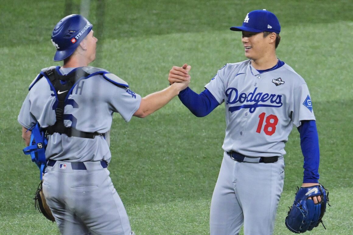 El lanzador de Los Angeles Dodgers Yoshinobu Yamamoto (der.) estrecha la mano con el receptor Will Smith después de la última entrada del juego dos de la Serie Mundial ante los Toronto Blue Jays. EFE/EPA/EDUARDO LIMA