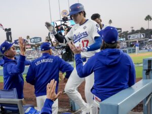 El bateador designado de los Los Angeles Dodgers, Shohei Ohtani (c), es recibido en el dugout después de conectar un jonrón en solitario contra los Azulejos de Toronto durante la tercera entrada del tercer juego de la Serie Mundial de la MLB. EFE/EPA/ALLISON DINNER