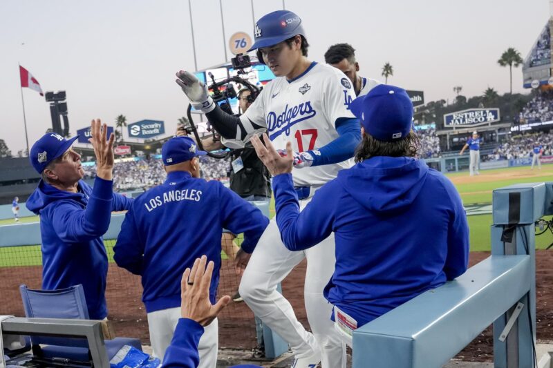 El bateador designado de los Los Angeles Dodgers, Shohei Ohtani (c), es recibido en el dugout después de conectar un jonrón en solitario contra los Azulejos de Toronto durante la tercera entrada del tercer juego de la Serie Mundial de la MLB. EFE/EPA/ALLISON DINNER