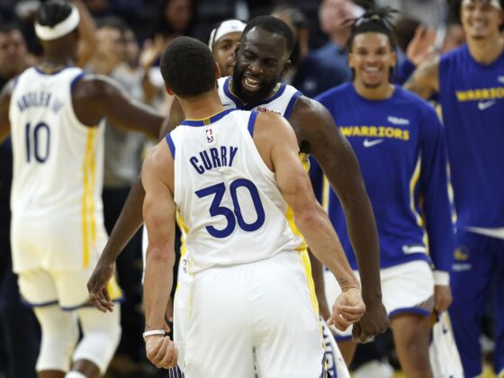 El base de los Golden State Warriors Stephen Curry (I) y el alero de los Golden State Warriors Draymond Green (C) reaccionan después de que Curry anotara durante la prórroga en el partido inaugural de los Golden State Warriors contra los Denver Nuggets en San Francisco, California, EE.UU. EFE/EPA/JOHN G. MABANGLO