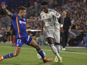 El delantero brasileño del Real Madrid, Vinicius Junior (d), intenta superar al defensa del Getafe, Kiko Femenía, durante el partido de la jornada 9 de LaLiga EA Sports que Getafe y Real Madrid disputaron en el Coliseum, en Getafe. EFE/Sergio Perez.