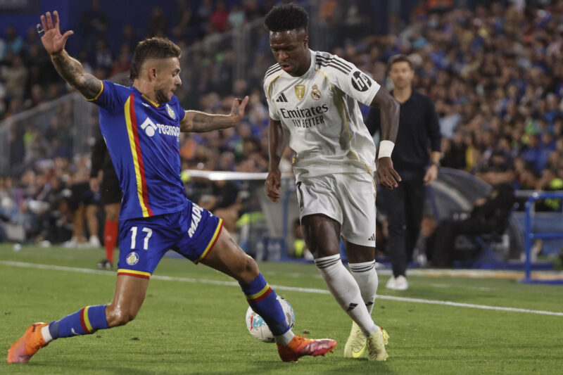 El delantero brasileño del Real Madrid, Vinicius Junior (d), intenta superar al defensa del Getafe, Kiko Femenía, durante el partido de la jornada 9 de LaLiga EA Sports que Getafe y Real Madrid disputaron en el Coliseum, en Getafe. EFE/Sergio Perez.