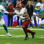 El jugador de los Washington Commanders con el balón ante los jugadores de los Miami Dolphins, durante el partido de liga regular de la Liga de Fútbol Americano (NFL), que este domingo disputan los equipos Miami Dolphins y Washington Commanders, este domingo en el Estadio Santiago Bernabéu. EFE/JuanJo Martín