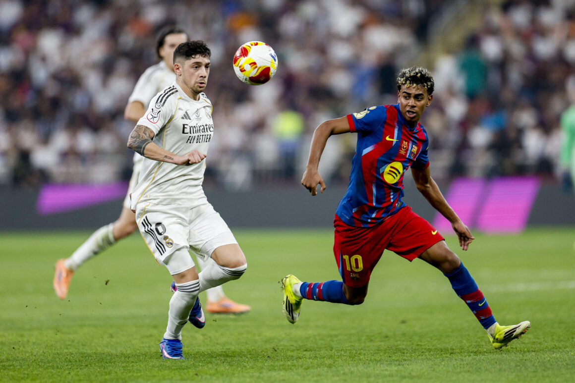 El delantero del FC Barcelona Lamine Yamal (d) disputa un balón con el centrocampista del Real Madrid Fede Valverde (i) durante la final de la Supercopa de España entre el FC Barcelona y el Real Madrid, el domingo 11 de enero en el estadio Ciudad Deportiva del Rey Abdalá de Yeda (Arab Saudí). EFE/ Kai Försterling