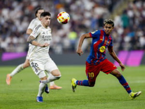 El delantero del FC Barcelona Lamine Yamal (d) disputa un balón con el centrocampista del Real Madrid Fede Valverde (i) durante la final de la Supercopa de España entre el FC Barcelona y el Real Madrid, el domingo 11 de enero en el estadio Ciudad Deportiva del Rey Abdalá de Yeda (Arab Saudí). EFE/ Kai Försterling