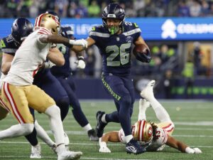 El corredor de los Seattle Seahawks, Zach Charbonnet (c), elude la marca de rivales de San Francisco 49ers durante el juego de la ronda divisiona, el 17 de enero pasado, poco antes de sufrir una delicada lesión que le hará perder el juego por el título de la Conferencia Nacional (NFC). EFE/EPA/JOHN G. MABANGLO
