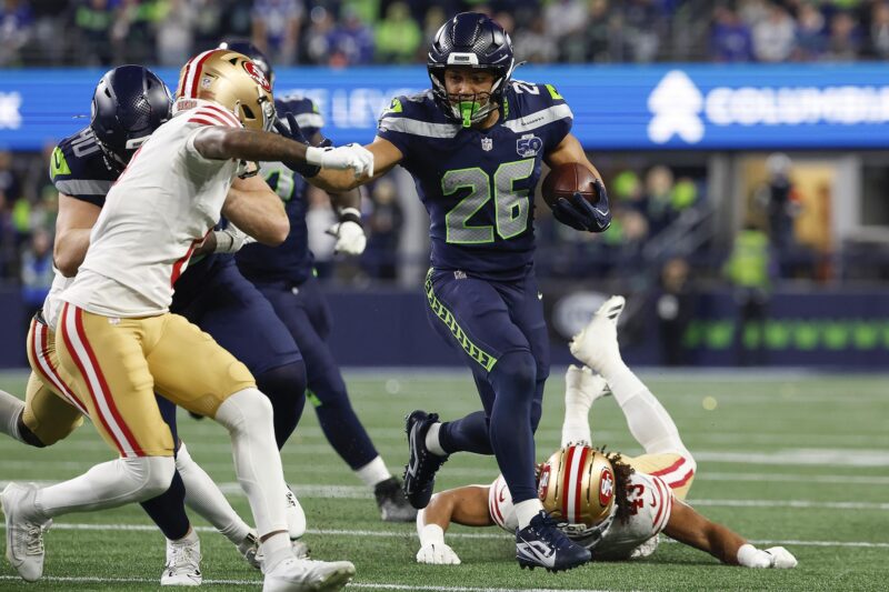 El corredor de los Seattle Seahawks, Zach Charbonnet (c), elude la marca de rivales de San Francisco 49ers durante el juego de la ronda divisiona, el 17 de enero pasado, poco antes de sufrir una delicada lesión que le hará perder el juego por el título de la Conferencia Nacional (NFC). EFE/EPA/JOHN G. MABANGLO