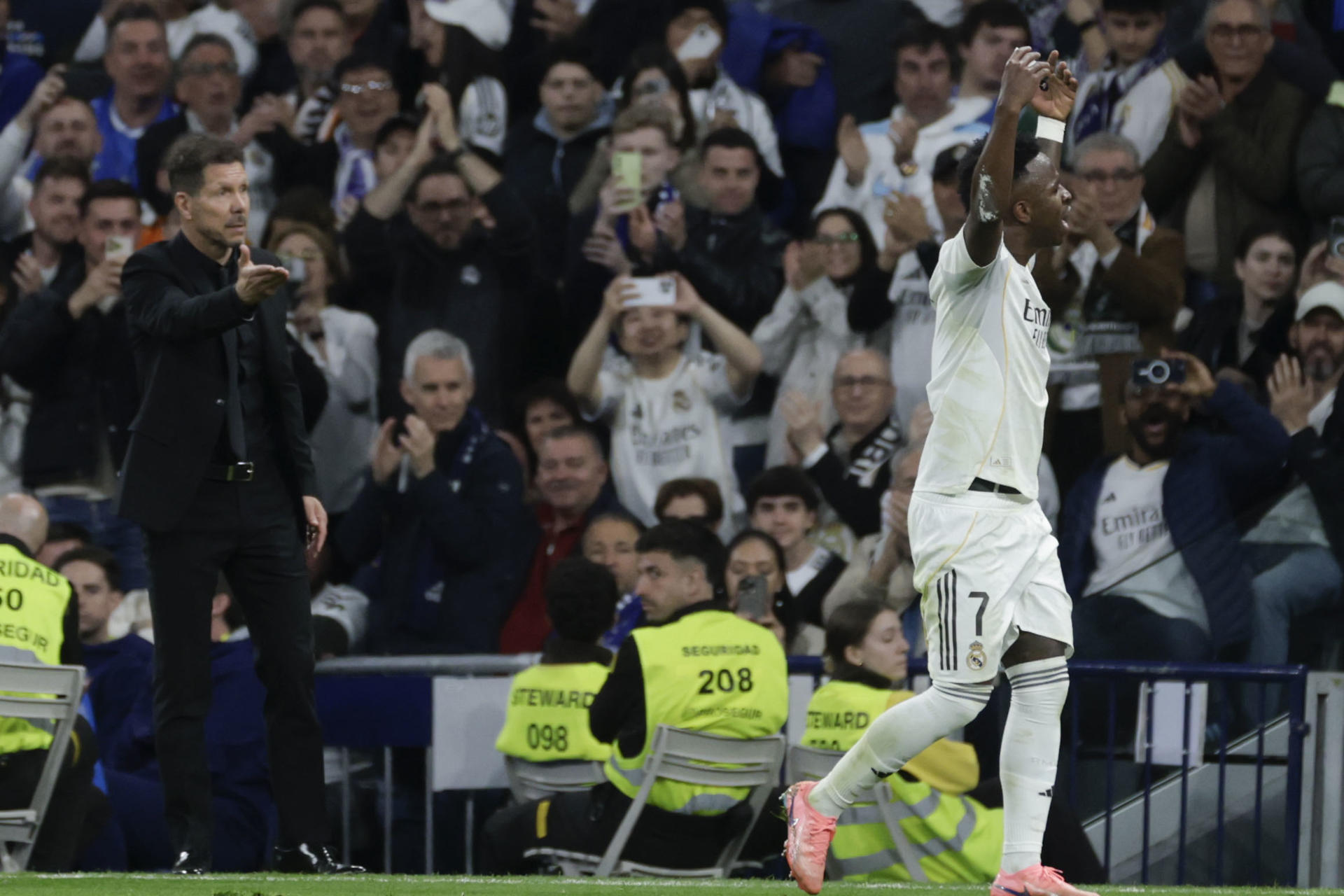 El delantero del Real Madrid Vinicius Junior (d) abandona el terreno de juega ante el técnico Diego Simeone, del Atlético, durante el partido de la jornada 29 de LaLiga que Real Madrid y Atlético de Madrid han disputado este domingo en el estadio Santiago Bernabéu. EFE/Juanjo Martín