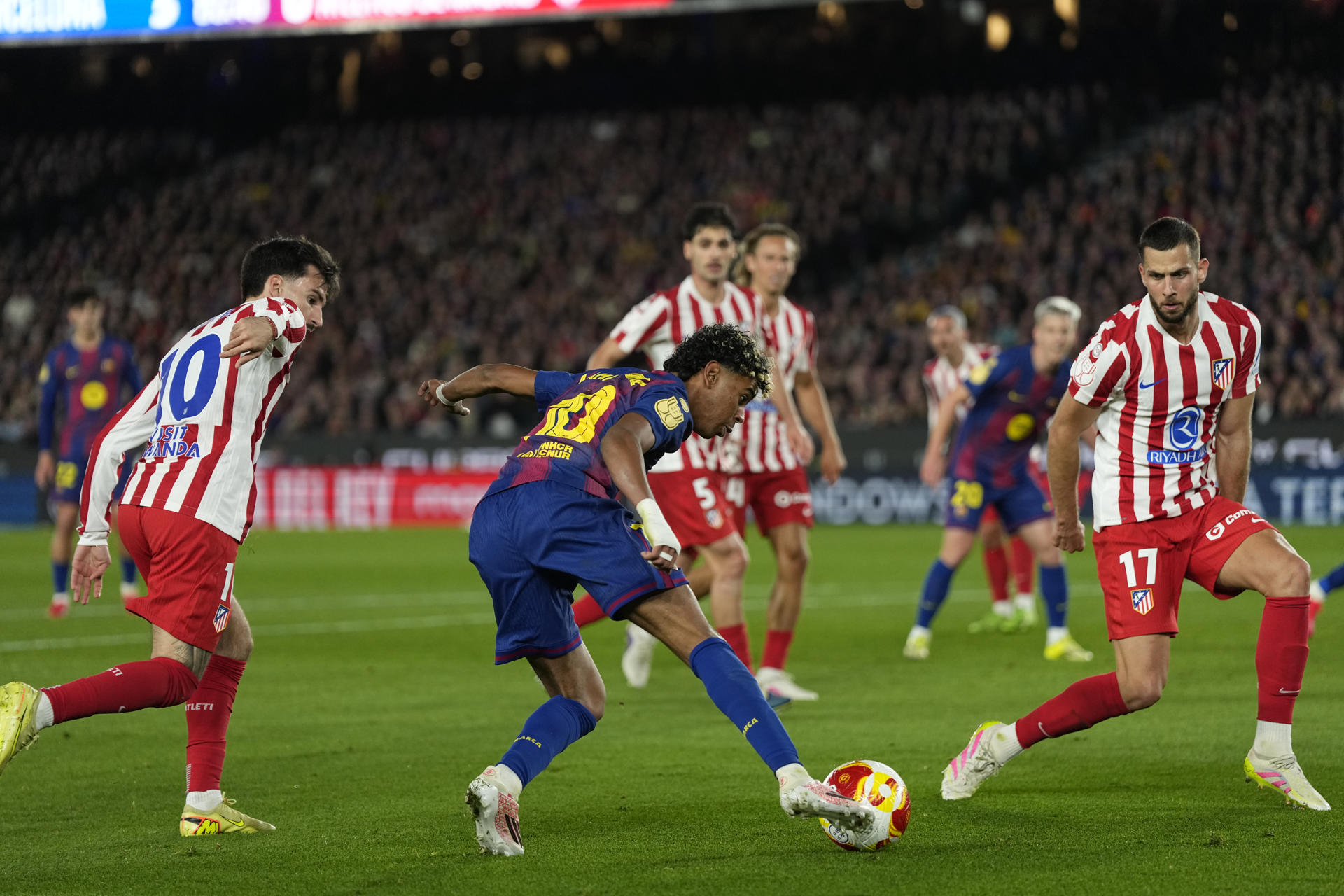 El delantero del Barcelona Lamine Yamal (c) intenta llevarse el balón ante los defensores del Atlético de Madrid durante el partido de vuelta de las semifinales de la Copa del Rey, en el Camp Nou. EFE/Siu Wu.